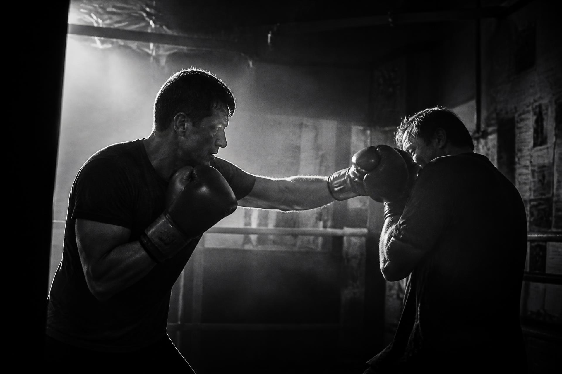 Twee leden van SAKAK sparren in een verduisterde kickboksgym